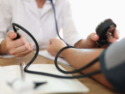 Close-up of doctors hand measuring blood pressure of male patient. Clinic or hospital office. Medicine and health care concept