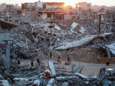 Palestinians walk in a devastated neighborhood due to Israeli strikes in the southern Gaza Strip city of Khan Yunis on December 2, 2024.