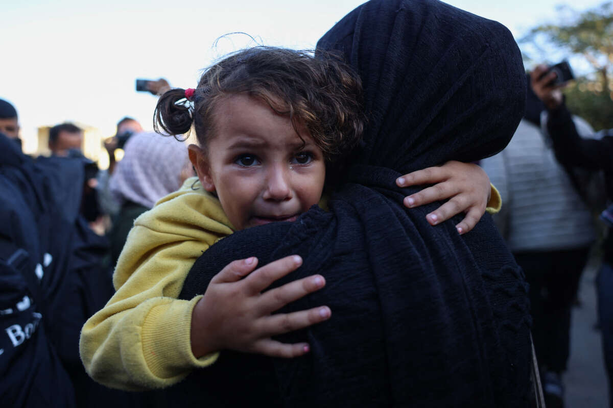 A girl cries as she's carried by a Palestinian woman mourning relatives killed in overnight Israeli strikes on the al-Mawasi cafeteria in southern Gaza's Khan Yunis, outside Nasser hospital on November 12, 2024.