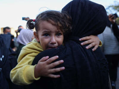 A girl cries as she's carried by a Palestinian woman mourning relatives killed in overnight Israeli strikes on the al-Mawasi cafeteria in southern Gaza's Khan Yunis, outside Nasser hospital on November 12, 2024.