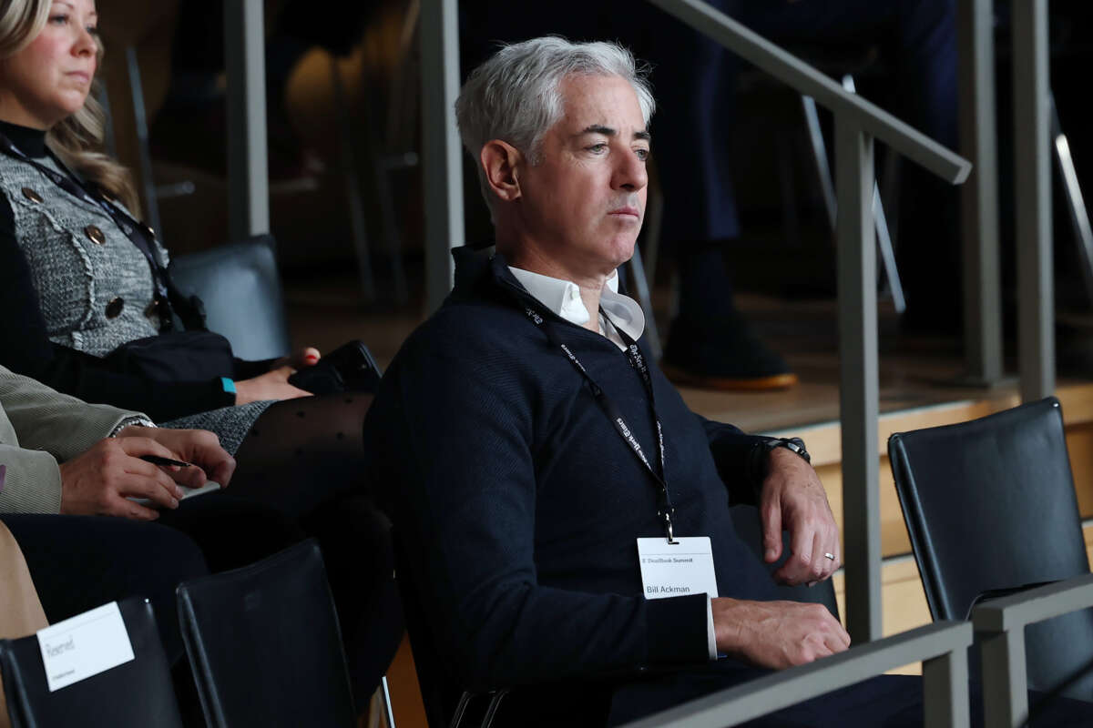 Bill Ackman, seated, looks onward at something superciliously