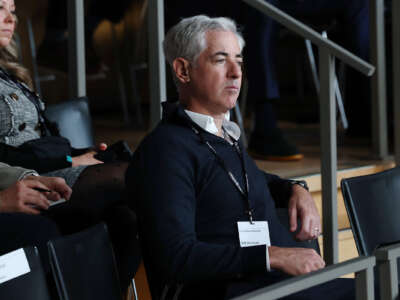 Bill Ackman, seated, looks onward at something superciliously