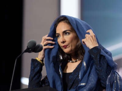 Harmeet Dhillon wears a blue veil while standing at a podium