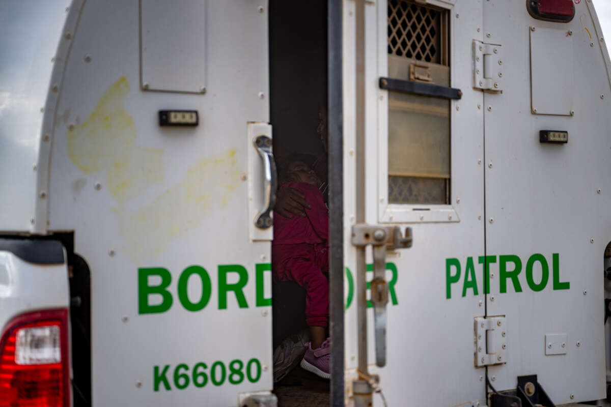 A woman holds her daughter in the back of a border patrol vehicle after being apprehended by U.S. Customs and Border Protection officers after crossing over into the U.S. on June 26, 2024, in Ruby, Arizona.