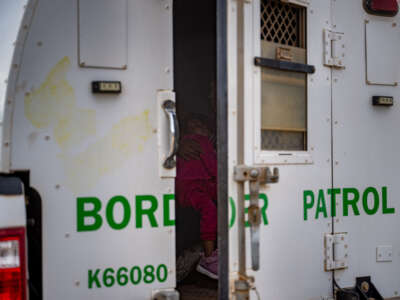 A woman holds her daughter in the back of a border patrol vehicle after being apprehended by U.S. Customs and Border Protection officers after crossing over into the U.S. on June 26, 2024, in Ruby, Arizona.