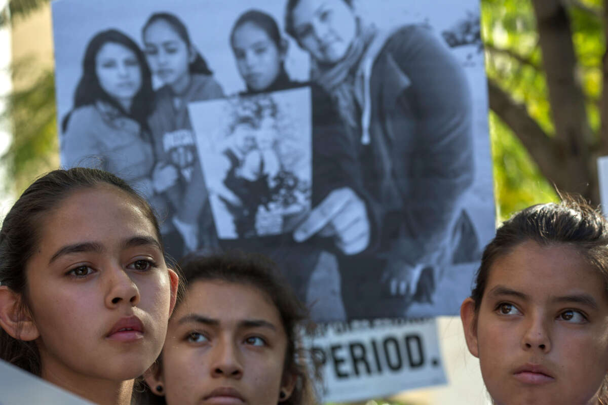 Daughters of Romulo Avelica-Gonzalez stand near a family photo as loved ones and supporters rally for his release outside U.S. Immigration and Customs Enforcement (ICE) offices on March 13, 2017, in Los Angeles, California. The 48-year-old father of four and long-time U.S. resident was arrested by ICE agents while taking his daughter to school.