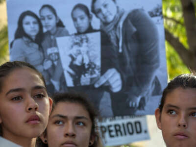 Daughters of Romulo Avelica-Gonzalez stand near a family photo as loved ones and supporters rally for his release outside U.S. Immigration and Customs Enforcement (ICE) offices on March 13, 2017, in Los Angeles, California. The 48-year-old father of four and long-time U.S. resident was arrested by ICE agents while taking his daughter to school.