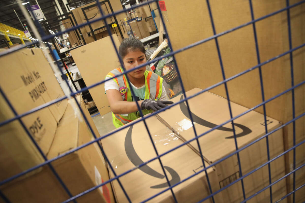 Workers pack and ship customer orders at the 750,000-square foot Amazon fulfillment center on August 1, 2017, in Romeoville, Illinois.