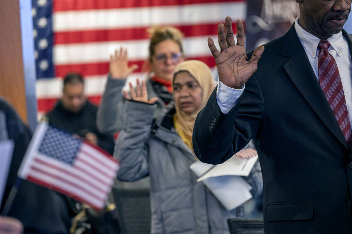 People raise their right hands as they become U.S. citizens