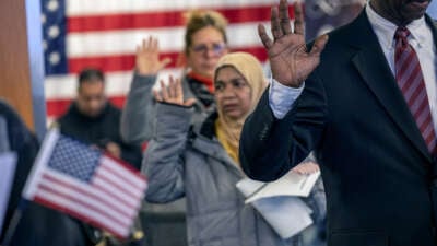 People raise their right hands as they become U.S. citizens