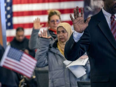 People raise their right hands as they become U.S. citizens