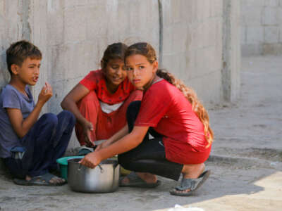 Displaced Palestinian children carry a food ration in Deir al-Balah in the central Gaza Strip on October 17, 2024.