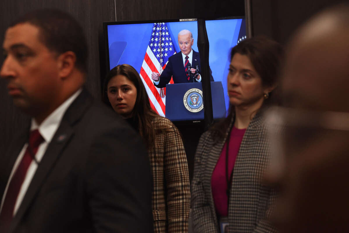 Joe Biden is seen delivering remarks on a television that every human being pictured has their back turned towards