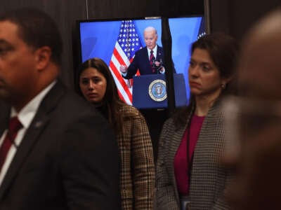 Joe Biden is seen delivering remarks on a television that every human being pictured has their back turned towards