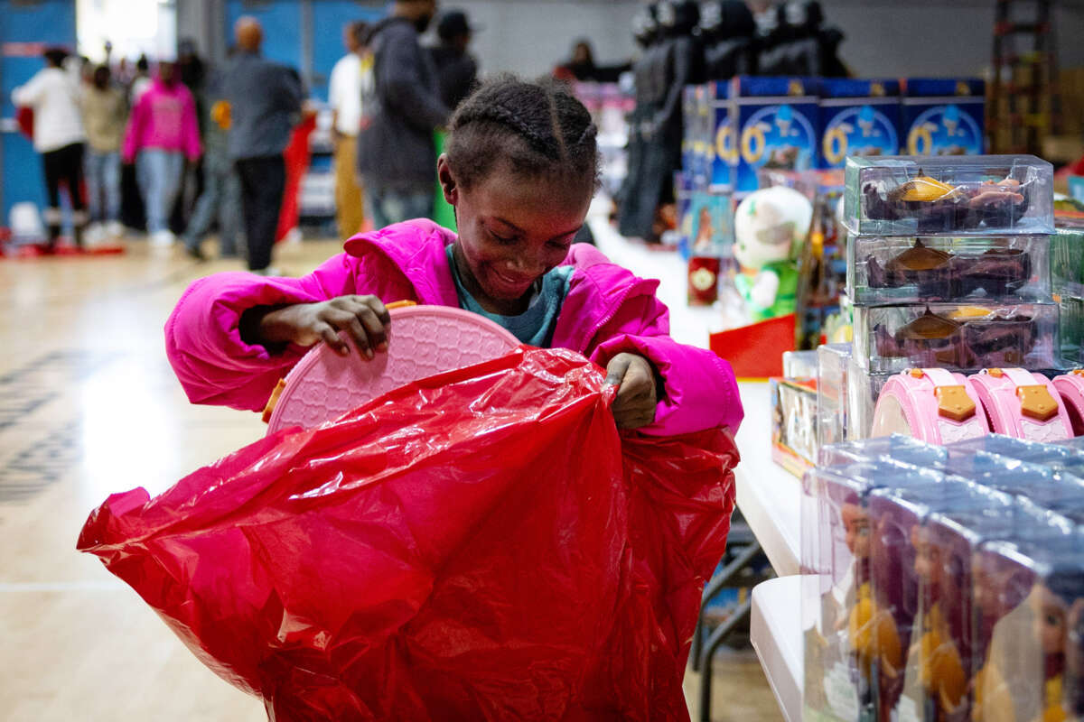 A little girl excitedly puts a gift into a red plastic bag