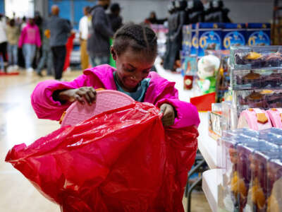 A little girl excitedly puts a gift into a red plastic bag