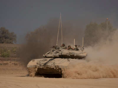 Israeli soldiers stand on a tank as it is moving a long the border with the Gaza Strip on August 29, 2024, in Southern Israel, Israel.