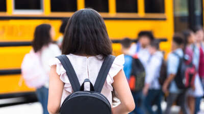 Students with backpacks approach school bus