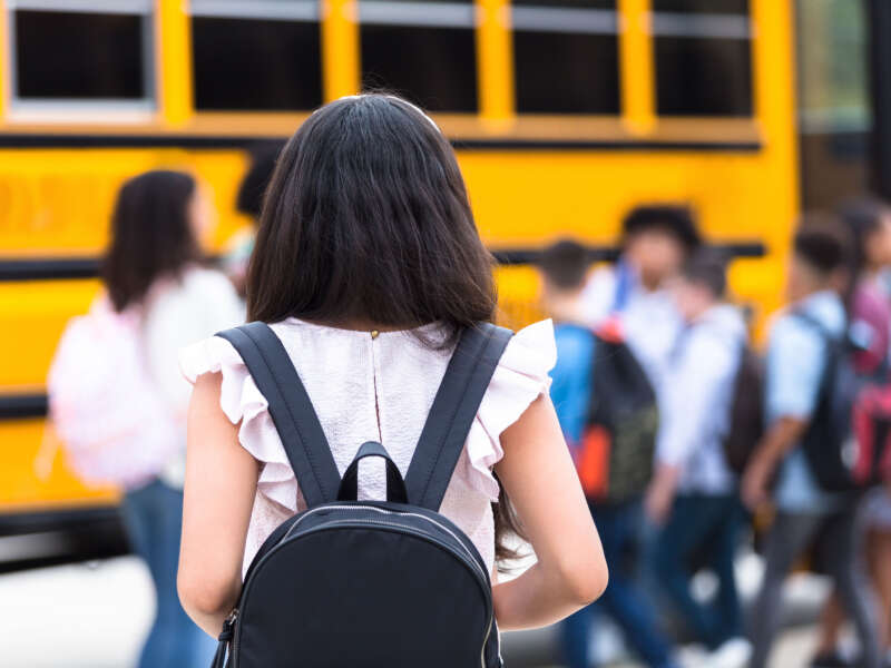 Students with backpacks approach school bus