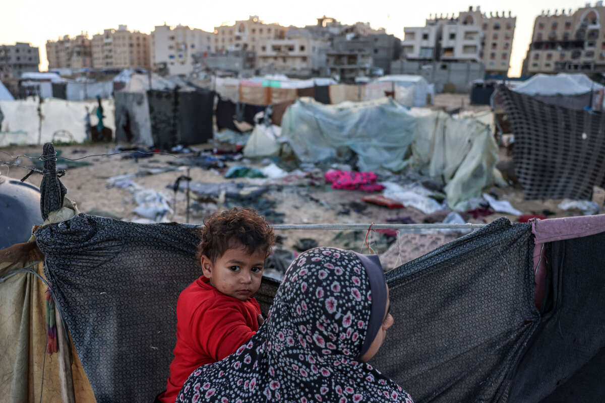 A woman holds a child near the site of reported Israeli bombardment on tents sheltering Palestinians displaced from Beit Lahia at a camp in Khan Yunis in the southern Gaza Strip on December 25, 2024.