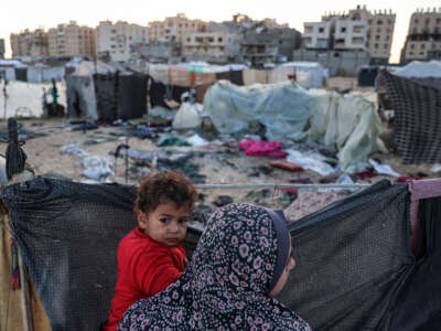 A woman holds a child near the site of reported Israeli bombardment on tents sheltering Palestinians displaced from Beit Lahia at a camp in Khan Yunis in the southern Gaza Strip on December 25, 2024.