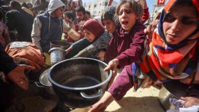 Palestinians gather to receive food cooked by a charity kitchen amid a hunger crisis in Deir el-Balah, Central Gaza Strip, on December 19, 2024.