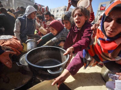 Palestinians gather to receive food cooked by a charity kitchen amid a hunger crisis in Deir el-Balah, Central Gaza Strip, on December 19, 2024.