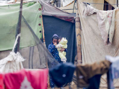 A child stands outside with a baby in the Gaza Strip on November 24, 2024, in a displaced persons camp after being displaced by Israeli airstrikes.