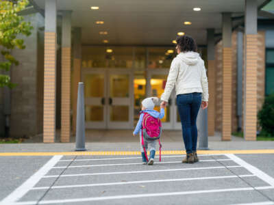 Mother and child walk hand in hand toward building