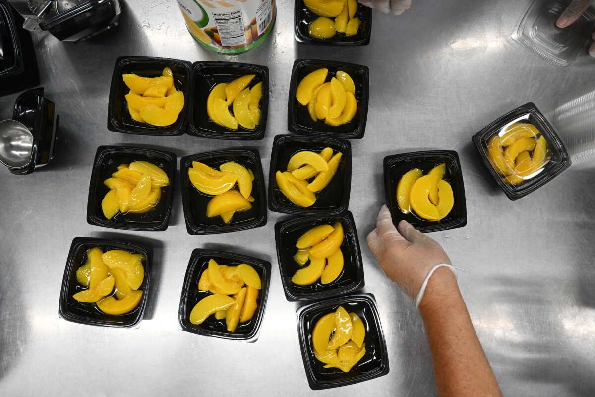 Peaches are put into containers for school lunch at Pembroke Elementary School on September 7, 2023, in Pembroke, North Carolina.