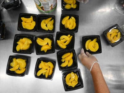 Peaches are put into containers for school lunch at Pembroke Elementary School on September 7, 2023, in Pembroke, North Carolina.