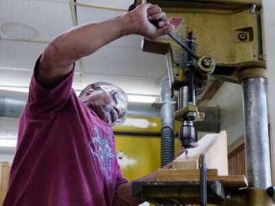 Enrique Suarez from Westport, uses a drill press to drill into a support brace that will be used in a picnic table at Essex Industries, a workshop that employs disabled people, on July 16, 2013, in Mineville, New York.