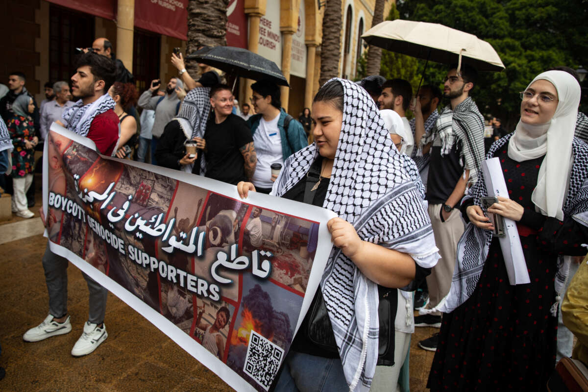 Students at the American University of Beirut hold up a sign demanding a boycott of companies working in Israel while protesting the genocide in Gaza on April 30, 2024, in Beirut, Lebanon.