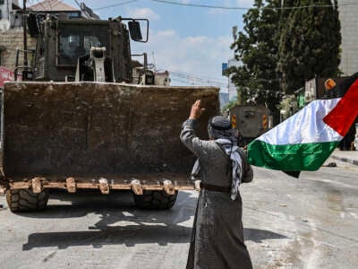 A Palestinian waves a Palestinian flag towards a bulldozer during an Israeli raid in the centre of Jenin, in the occupied West Bank, Palestine, on September 2, 2024.