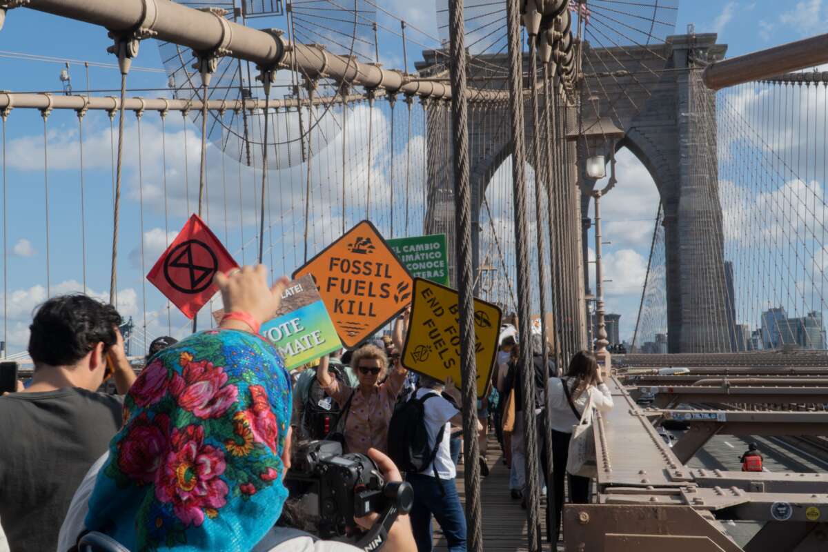 Protesters hold climate signs as they march across the Brooklyn Bridge as part of the Youth Climate Strike, filling the pedestrian promenade on their way to Brooklyn Borough Hall for a rally. Their signs carry various environmental and climate slogans and demands such as Fossil Fuels Kill; Vote Climate; and Biden End Fossil Fuels.