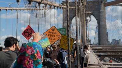 Protesters hold climate signs as they march across the Brooklyn Bridge as part of the Youth Climate Strike, filling the pedestrian promenade on their way to Brooklyn Borough Hall for a rally. Their signs carry various environmental and climate slogans and demands such as Fossil Fuels Kill; Vote Climate; and Biden End Fossil Fuels.