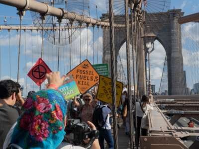 Protesters hold climate signs as they march across the Brooklyn Bridge as part of the Youth Climate Strike, filling the pedestrian promenade on their way to Brooklyn Borough Hall for a rally. Their signs carry various environmental and climate slogans and demands such as Fossil Fuels Kill; Vote Climate; and Biden End Fossil Fuels.