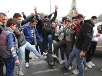 Syrians pose with a vandalized statue of Hafez al-Assad, father of Bashar al-Assad, in Umayyad Square on December 8, 2024, in Damascus, Syria.