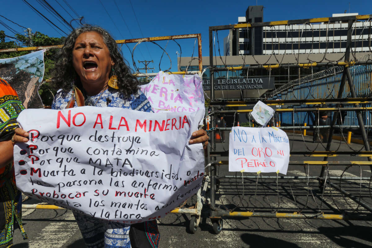 An indigenous woman shouts slogans while holding an sign in front of a riot police barricade during a protest by members of organizations and communities against mining in front of the Legislative Assembly of El Salvador on December 23, 2024, in San Salvador, El Salvador.