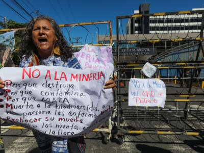 An indigenous woman shouts slogans while holding an sign in front of a riot police barricade during a protest by members of organizations and communities against mining in front of the Legislative Assembly of El Salvador on December 23, 2024, in San Salvador, El Salvador.