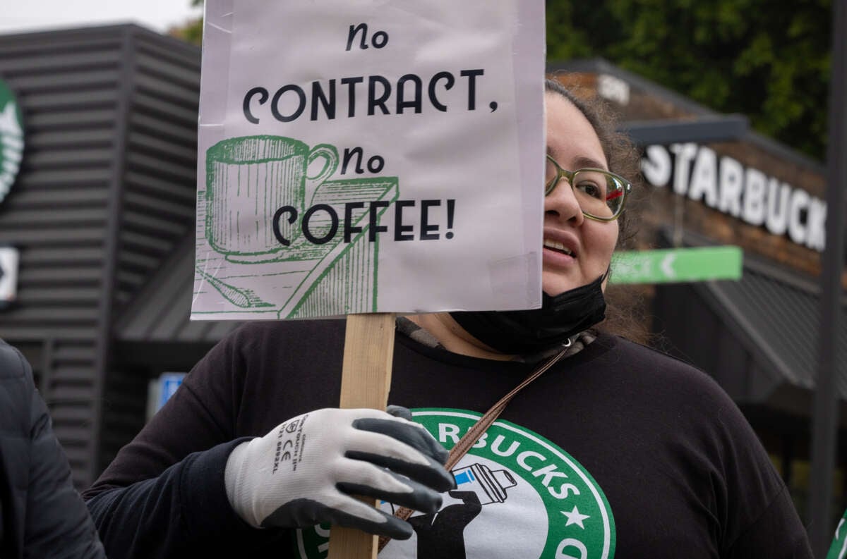 A Starbucks barista holds a sign as workers picket at a store in Cypress Park, CA.