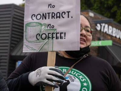 A Starbucks barista holds a sign as workers picket at a store in Cypress Park, CA.