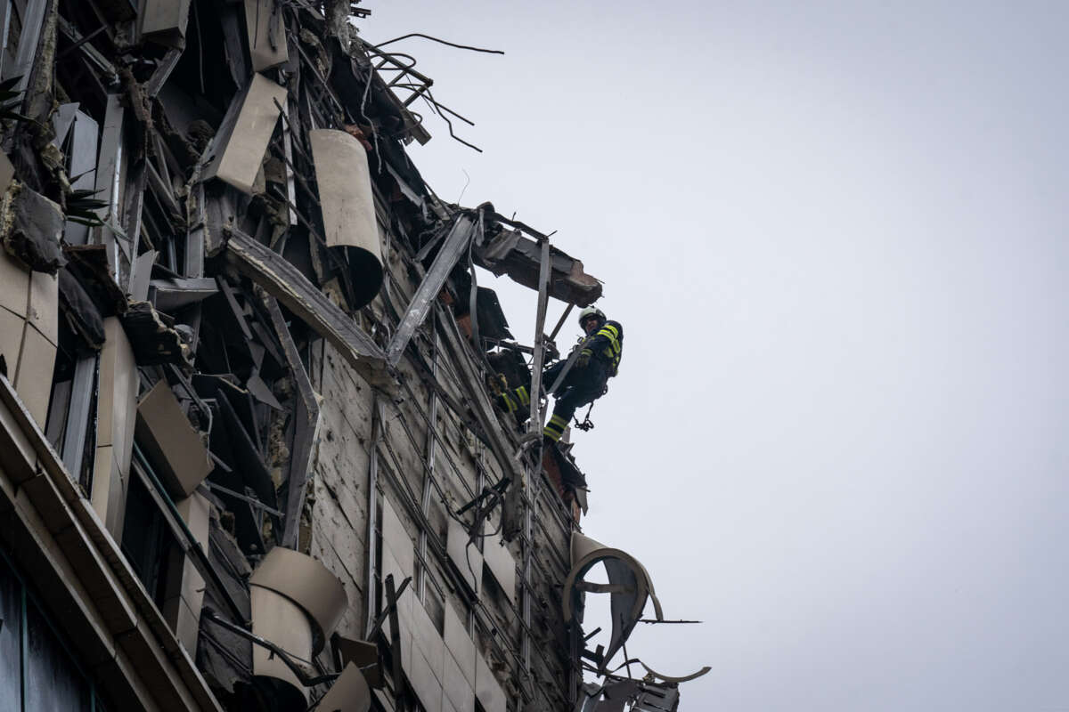 A firefighter rappels down the side of a destroyed building