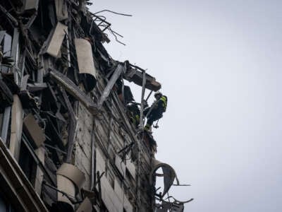 A firefighter rappels down the side of a destroyed building