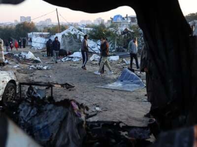 Displaced Palestinians walk amid scattered debris of tents on January 2, 2025, following an overnight Israeli strike on a makeshift displacement camp in Mawasi Khan Yunis in the southern Gaza Strip, that reportedly killed at least 11 people, including the chief of the territory's now dismantled Hamas police force.