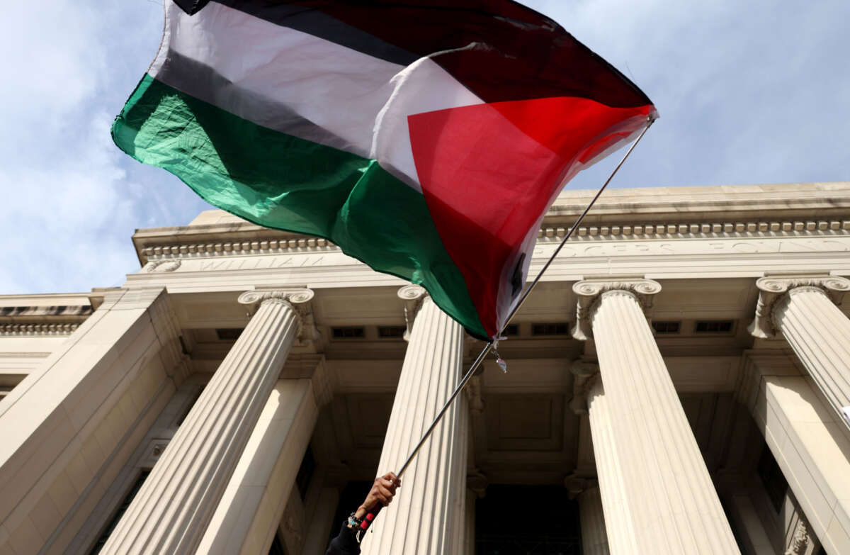 A protester waves a Palestinian flag outside of MIT during a Students and Workers Unite for Palestine May Day Rally at MIT on May 1, 2024.