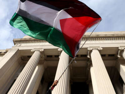 A protester waves a Palestinian flag outside of MIT during a Students and Workers Unite for Palestine May Day Rally at MIT on May 1, 2024.