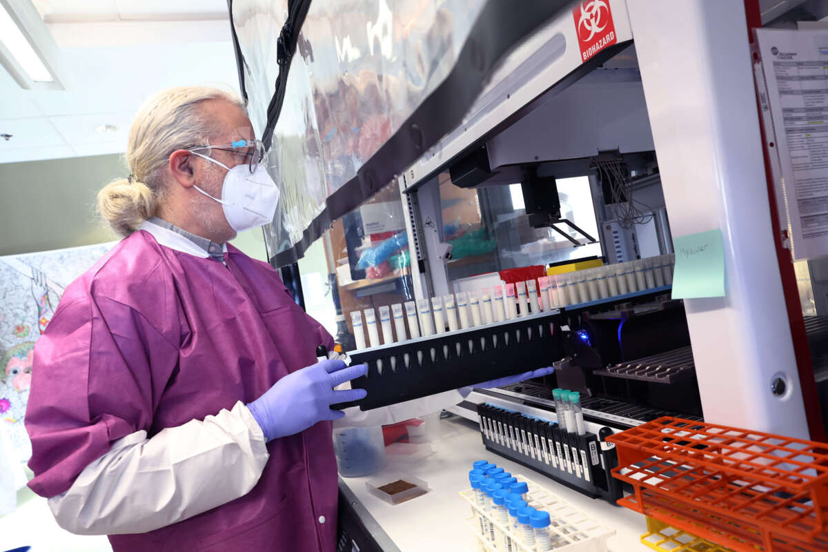 A scientist puts vials of milk into equipment for testing