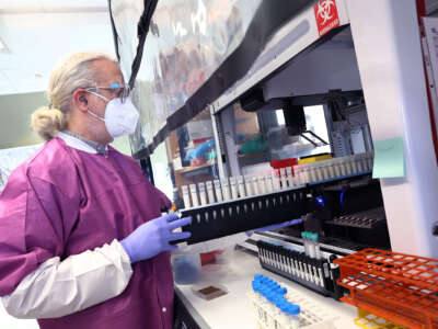 A scientist puts vials of milk into equipment for testing