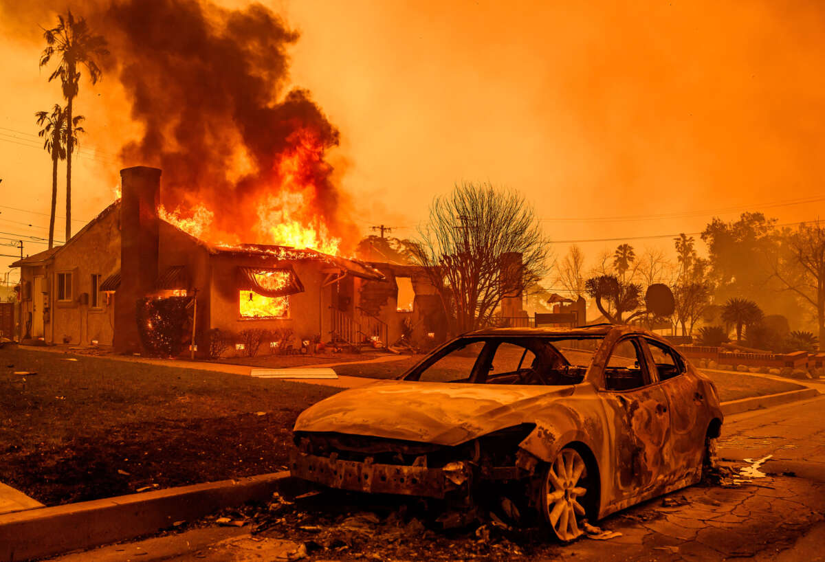 The carcass of a burnt-out car is seen as home burns during the Eaton Fire in the Altadena area of Los Angeles County, California, on January 8, 2025.